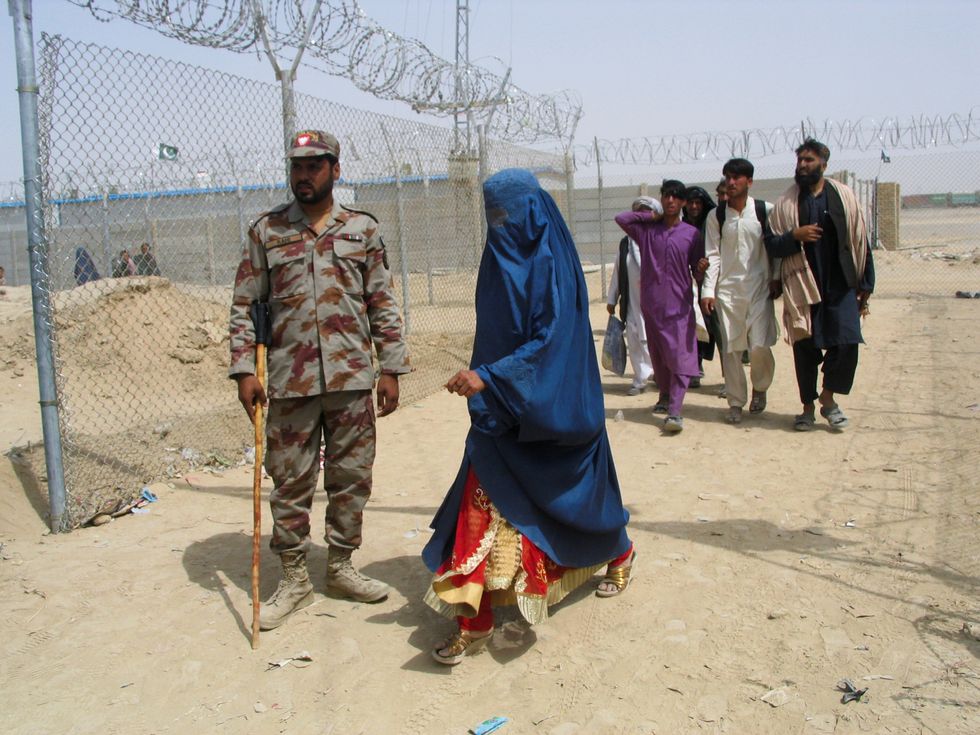 An Afghan woman clad in a burqa walks past Pakistan's paramilitary soldier, as she along with others enter Pakistan via Friendship Gate crossing point at the Pakistan-Afghanistan border town of Chaman, Pakistan August 17, 2021. REUTERS/Saeed Ali Achakzai