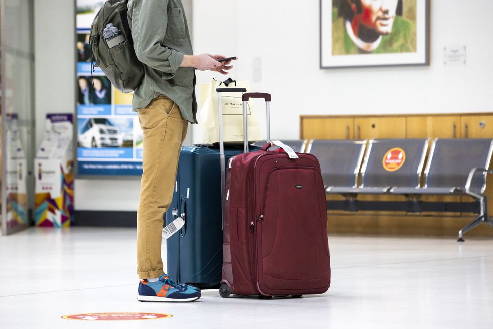 An air passenger standing with luggage in George Best Belfast City Airport.