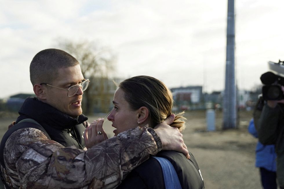 An American couple embraces after crossing the border and fleeing the violence in Ukraine, in Medyka, Poland, February 24, 2022. REUTERS/Bryan Woolston
