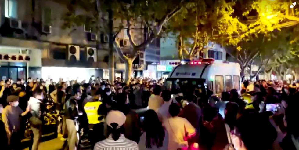 An angry mob confronts a police riot van in Shanghai as protests sweep China
