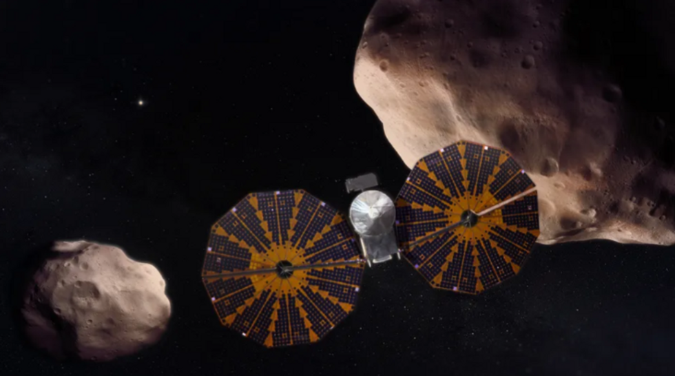 An artist's depiction of the Lucy spacecraft flying past a pair of Trojan asteroids