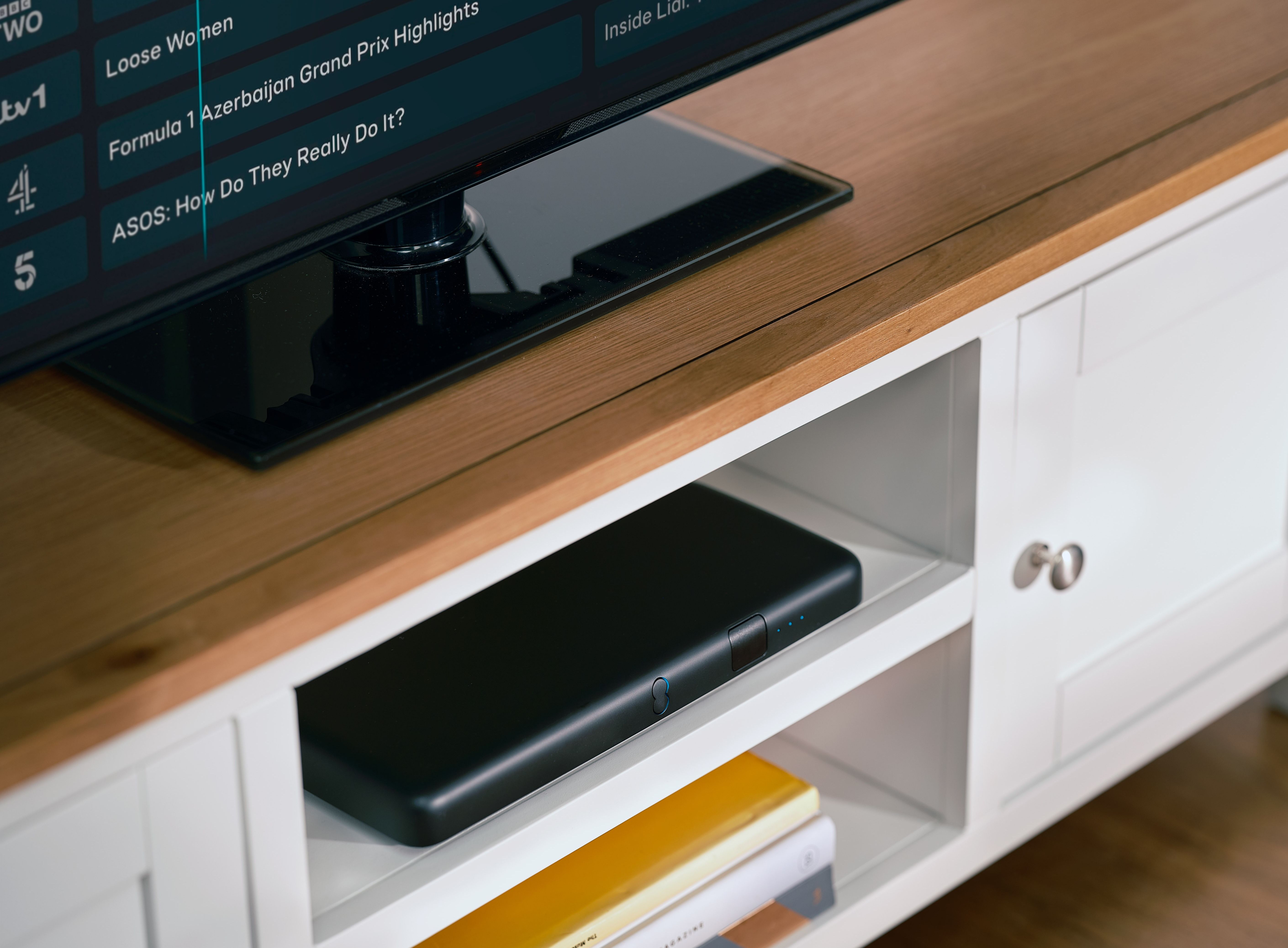 an ee set-top box pictured in a media unit underneath a large television