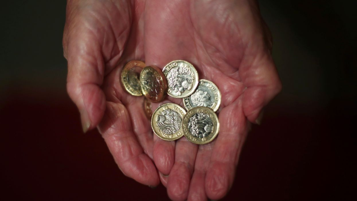 An elderly woman holding pound coins in her hands