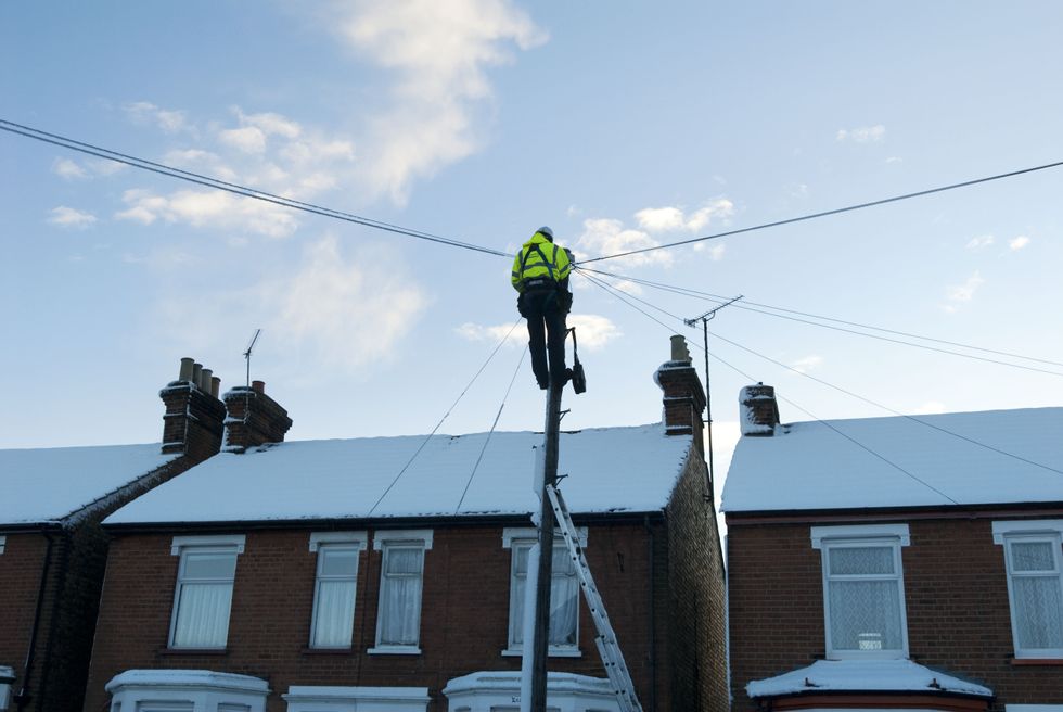 an engineer is pictured on a telegraph pole fixing wiring