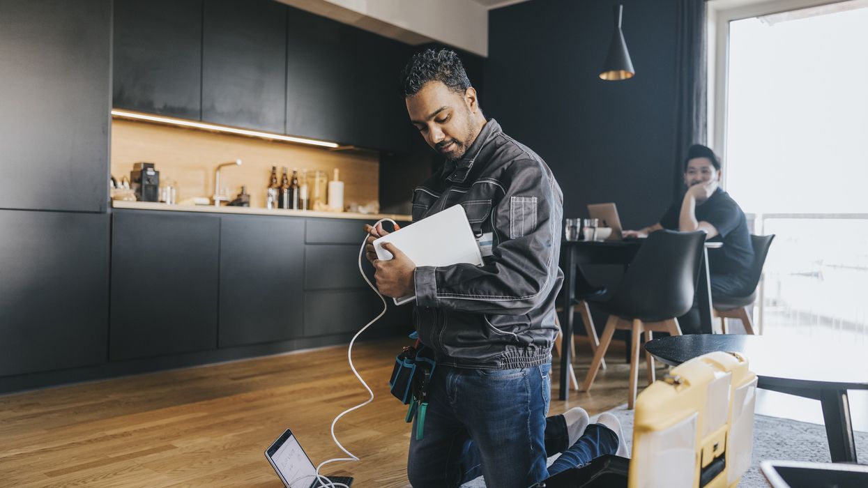 an engineer is pictured wiring a broadband router for a customer in their home