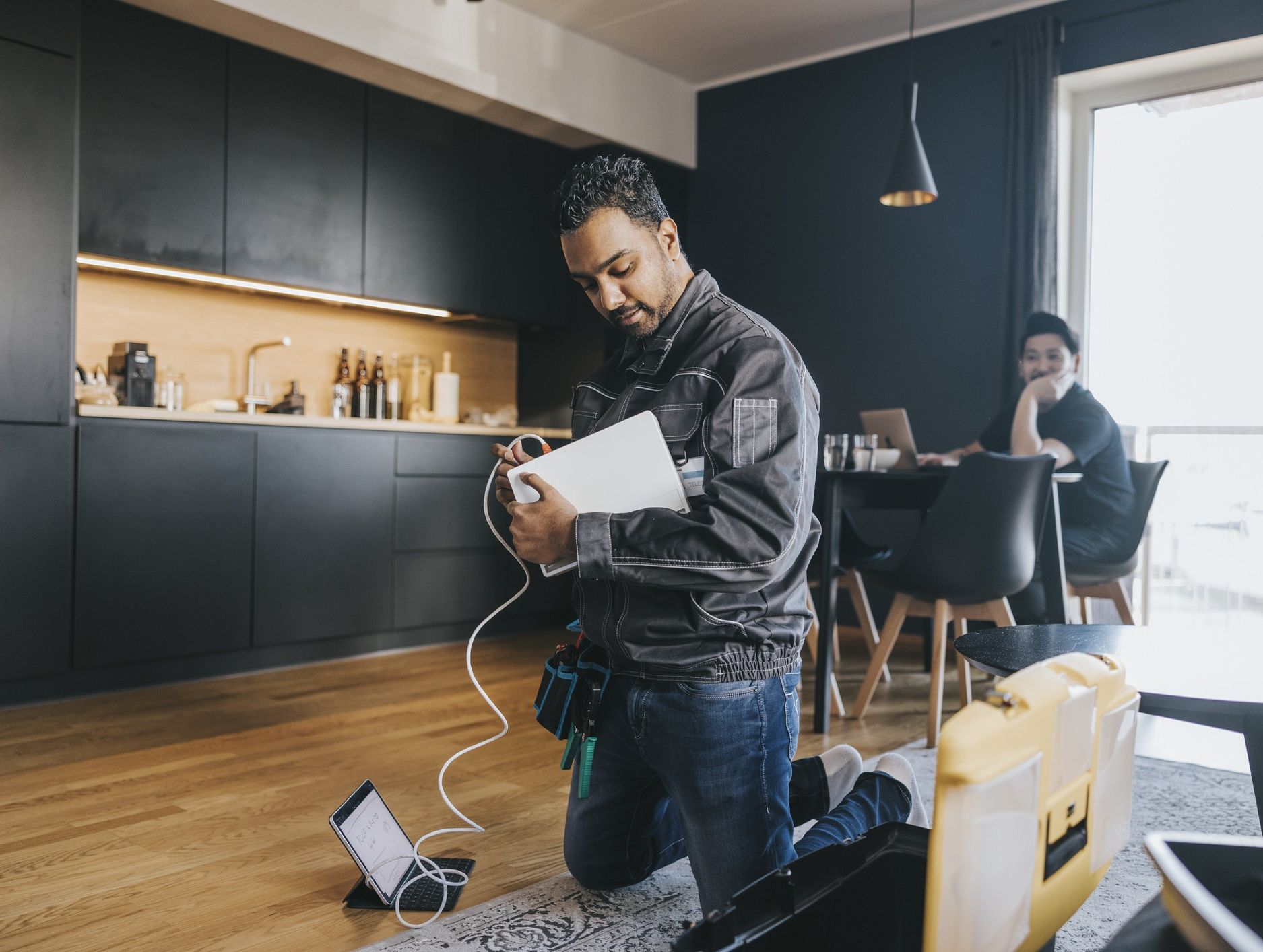 an engineer is pictured wiring a broadband router for a customer in their home