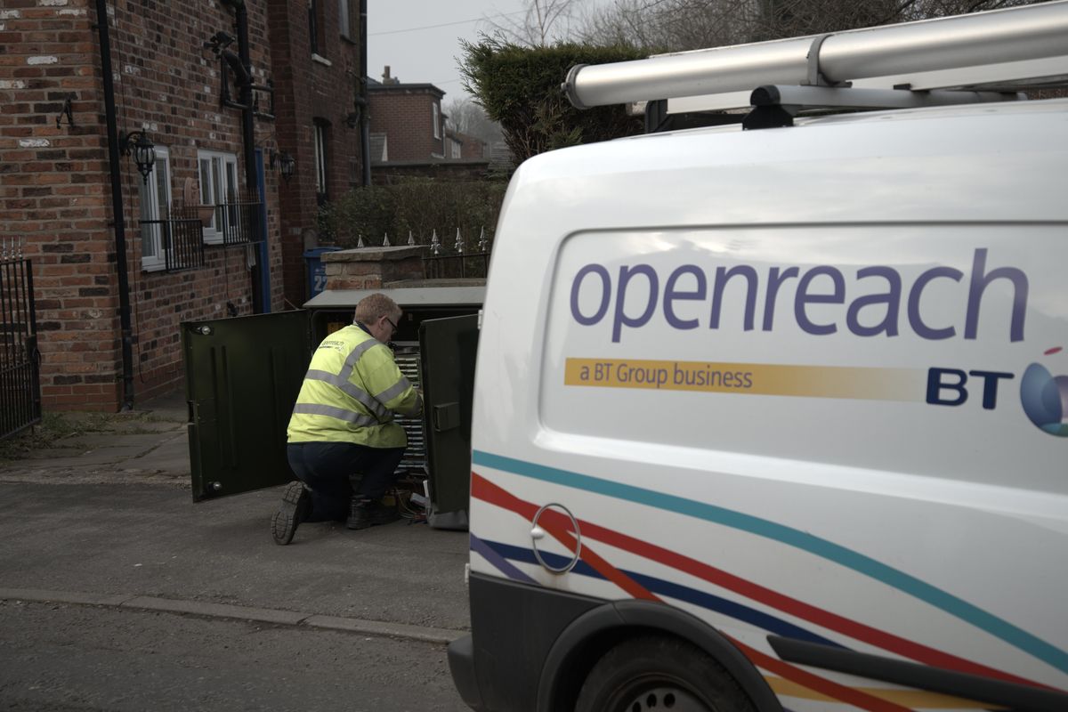 an engineer is pictured working on an exchange cabinet with the openreach branded van in the foreground