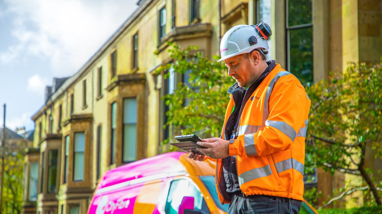 an engineer stands outside with a tablet and a cityfibre branded van in the background