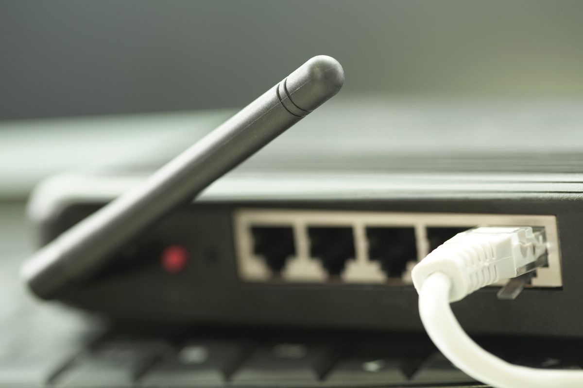 an ethernet cable is pictured plugged into the back of a Wi-Fi router