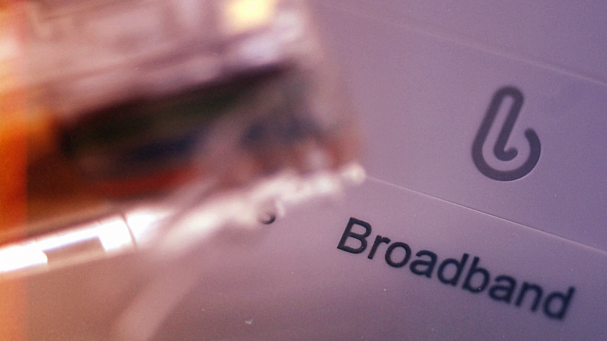 an ethernet cable pictured on the left-side of the image, with a Wi-Fi router with the word "broadband" visible fills the rest of the frame