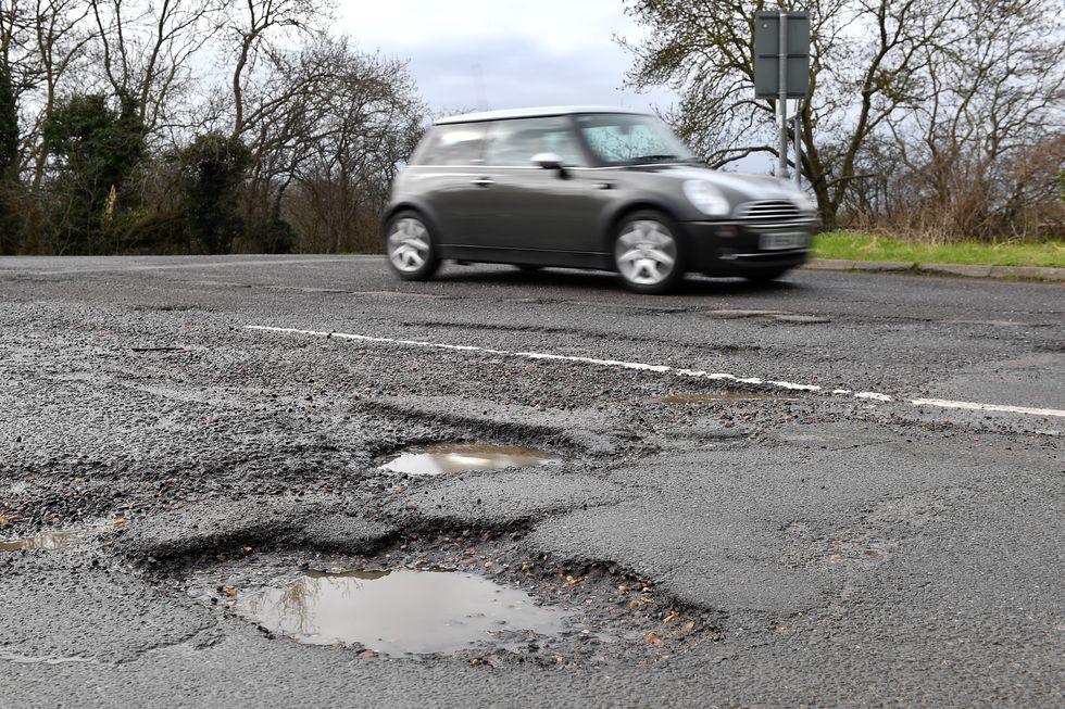An image of a car driving past a pothole