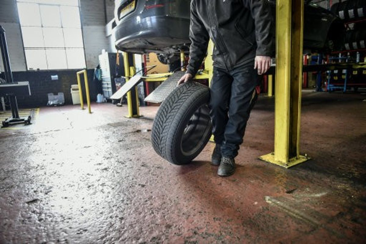 An image of a mechanic holding a tyre