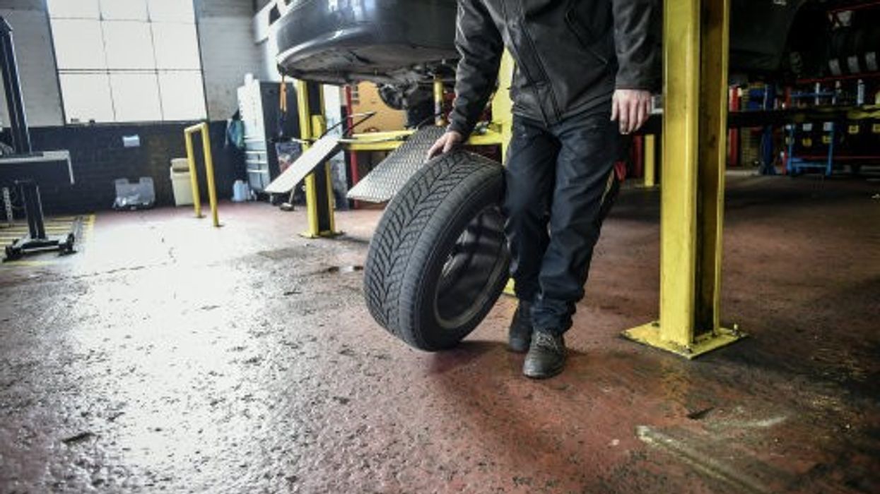 An image of a mechanic holding a tyre
