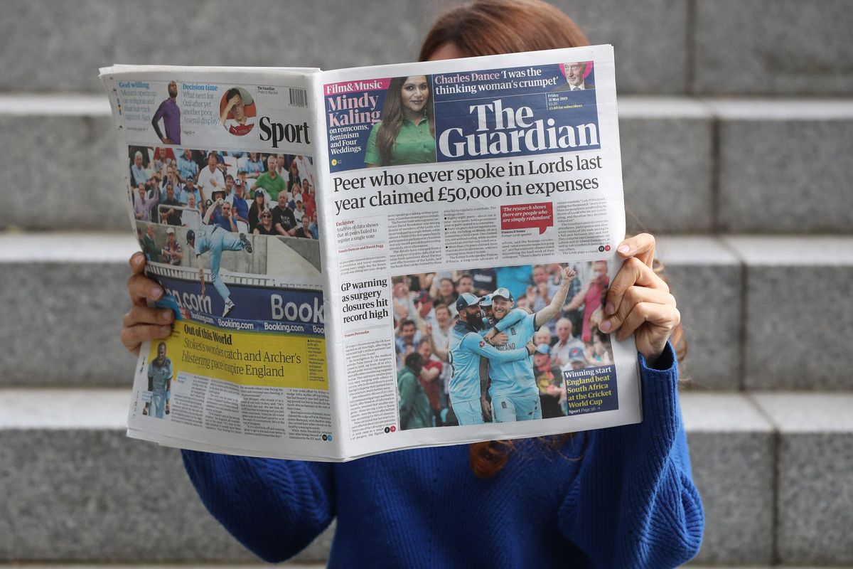 An image of a woman holding a copy of The Guardian