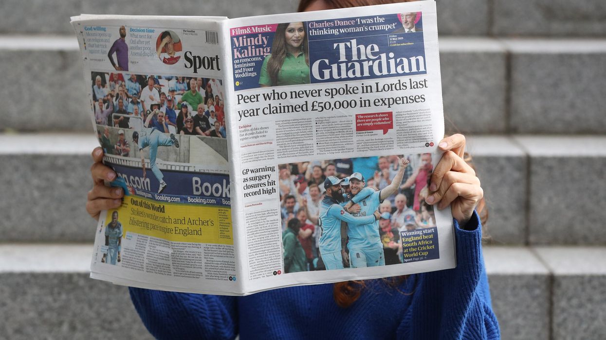 An image of a woman holding a copy of The Guardian