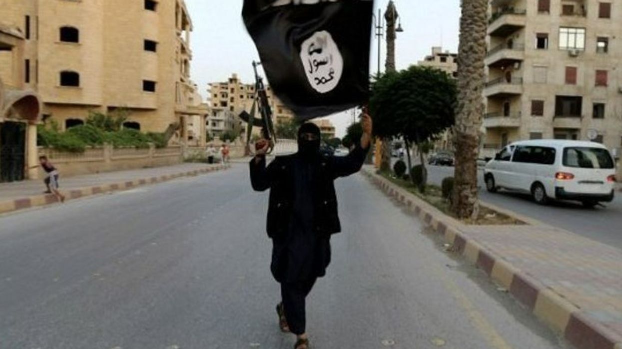 An image of an Isis fighter flying an Isis flag