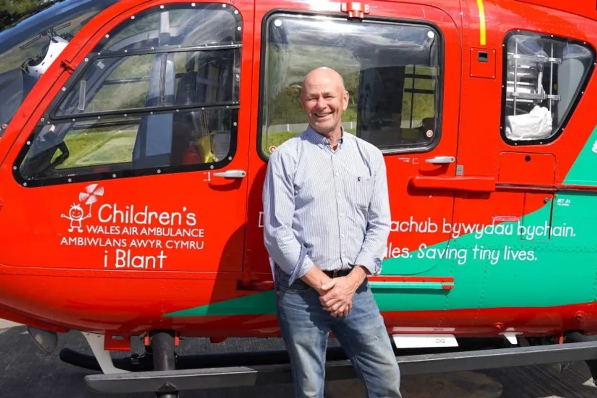 An image of Brendan Clancy with a Welsh Air Ambulance helicopter