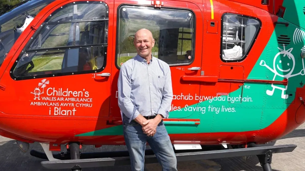 An image of Brendan Clancy with a Welsh Air Ambulance helicopter