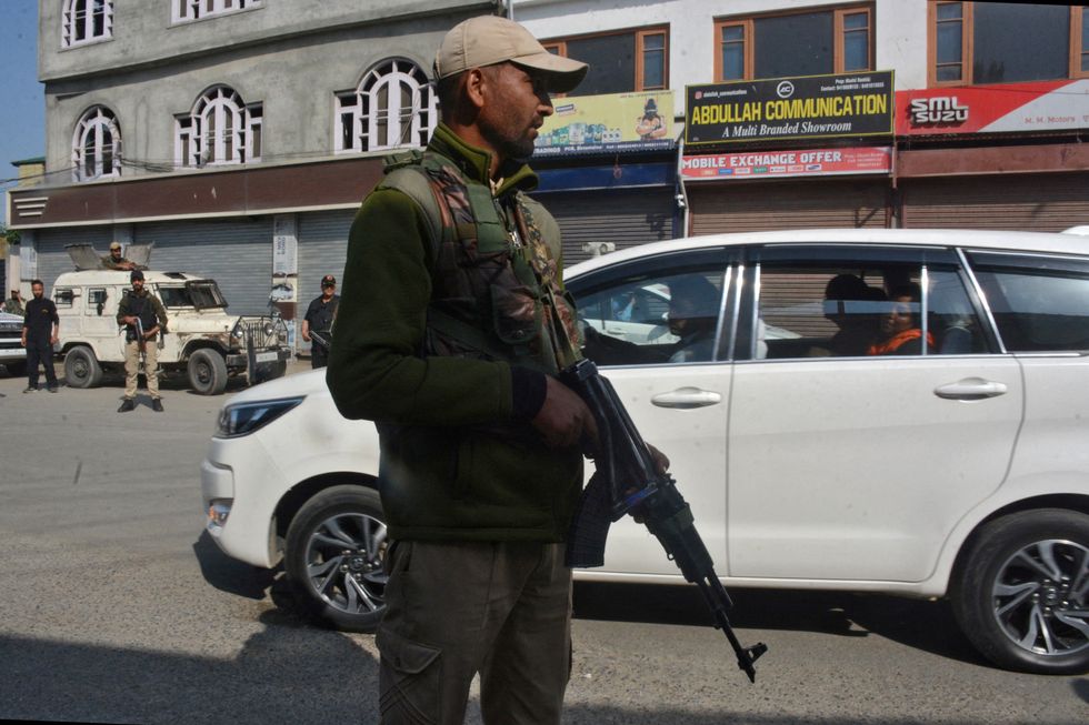 An Indian police officer stands guard as a vehicle carrying the relatives of the tourists who were killed in a suspected militant attack near Pahalgam, arrives at the police control room in Srinagar