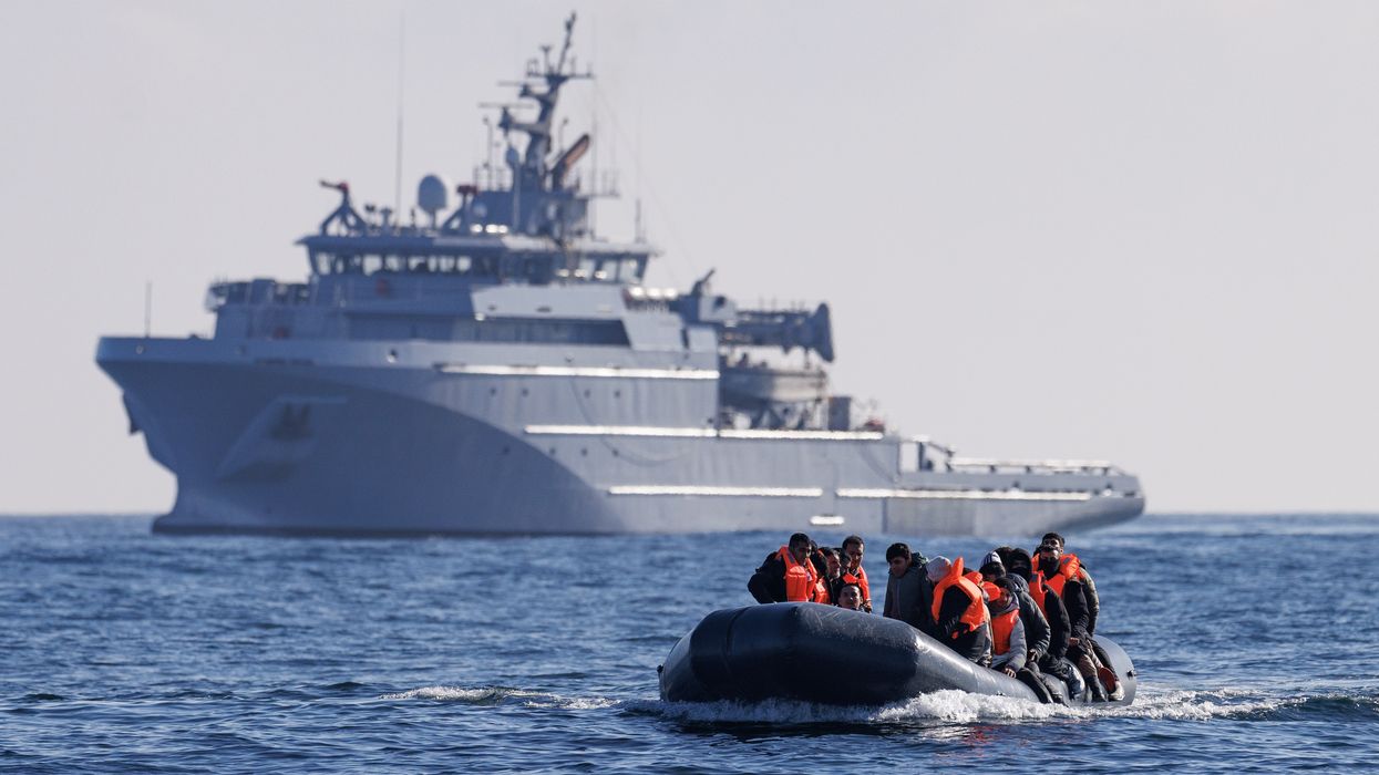 An inflatable dinghy carrying migrants is escorted by a French Warship across the English Channel