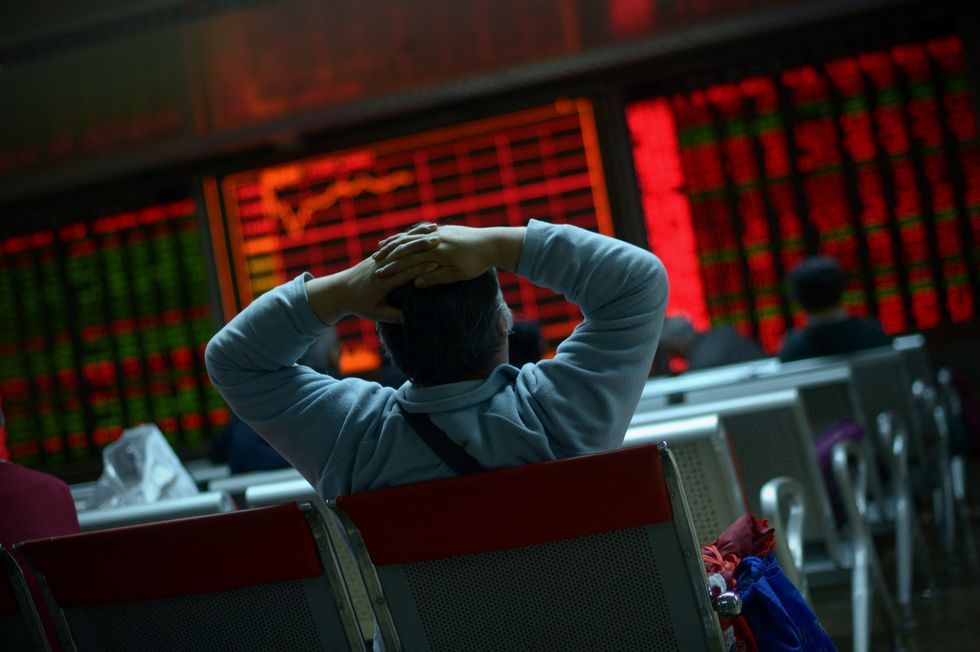 An investor looks at screens showing stock market movements at a securities company in Beijing