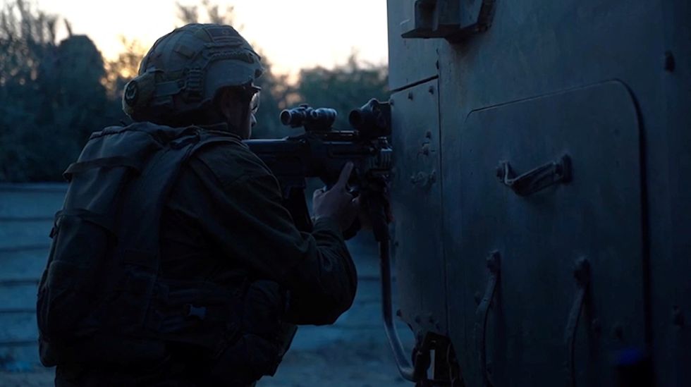 An Israeli soldier holds a weapon from behind a military vehicle in a location given as Gaza