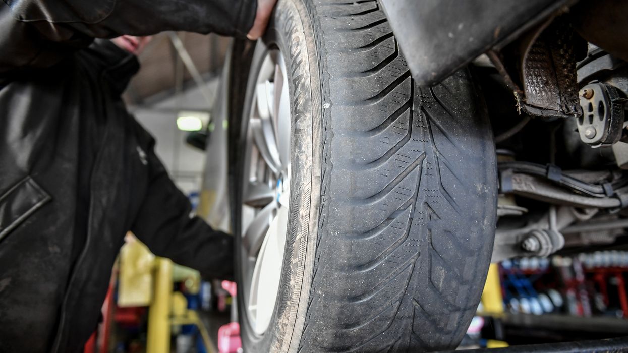 An MOT tester checking a tyre