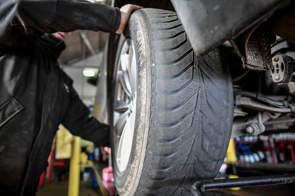 An MOT tester checking a tyre