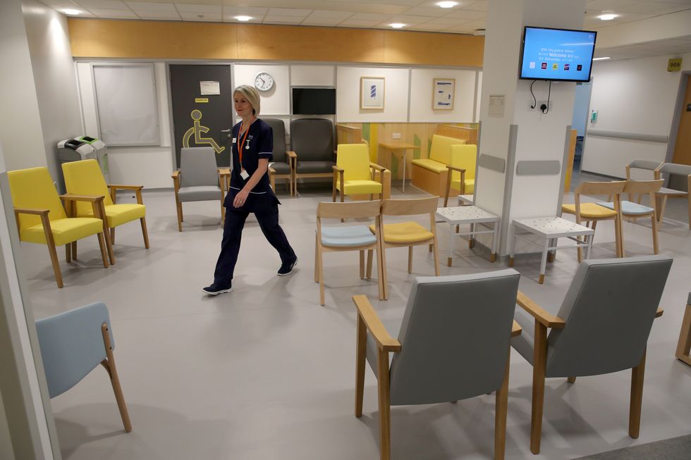 An NHS nurse walks through the waiting room in Outpatients Department