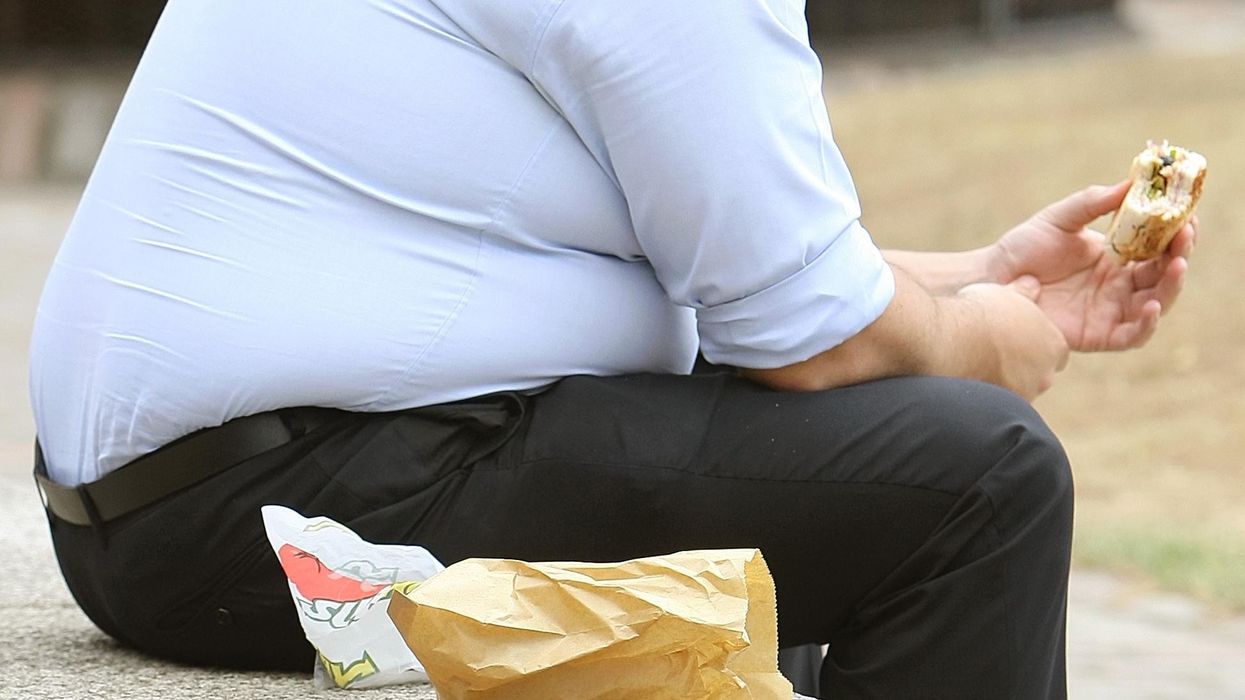 An obese man eating a burger