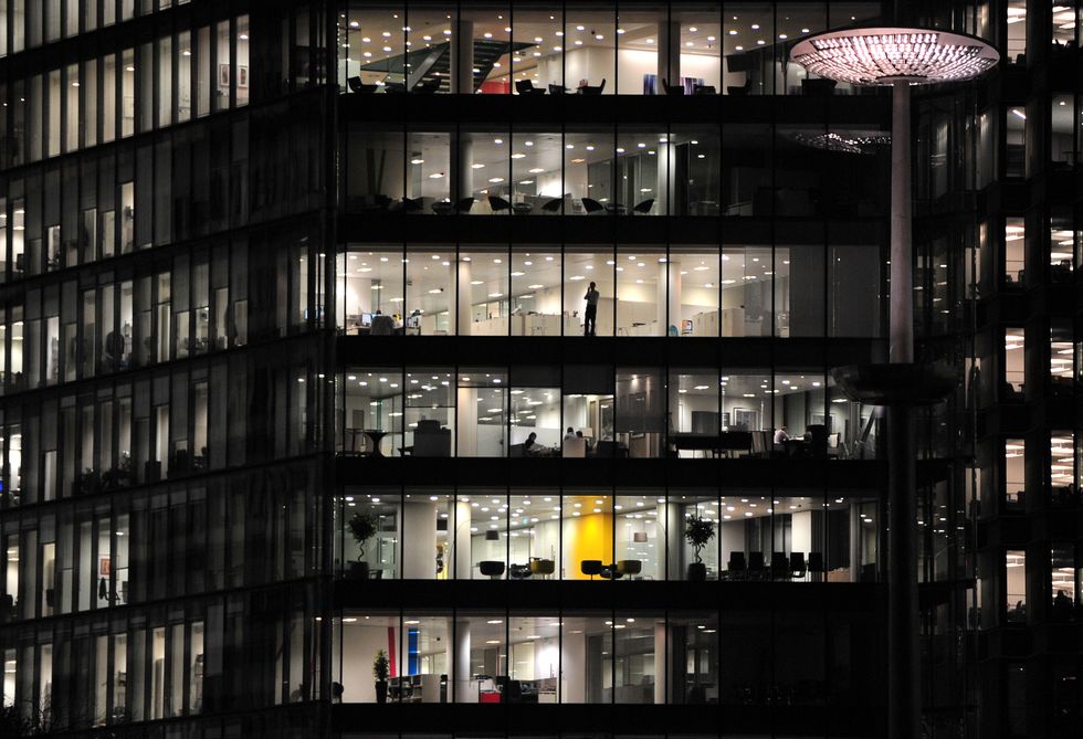 An office worker using a mobile phone in the window of an office block along the River Thames near More London