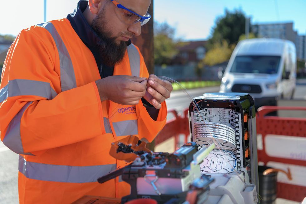 an openreach engineer wires up a fibre optic cable in an exchange cabinet