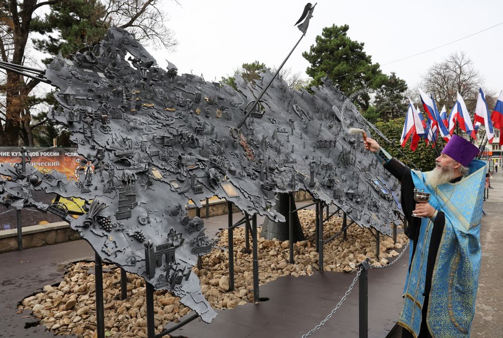 An Orthodox priest blesses an installation depicting a map of Russia with Russian-controlled regions of Ukraine on National Unity Day, in Simferopol, Crimea, November 4, 2023.