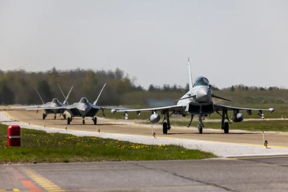 An RAF fighter jet followed by two USAF F-22 Raptors
