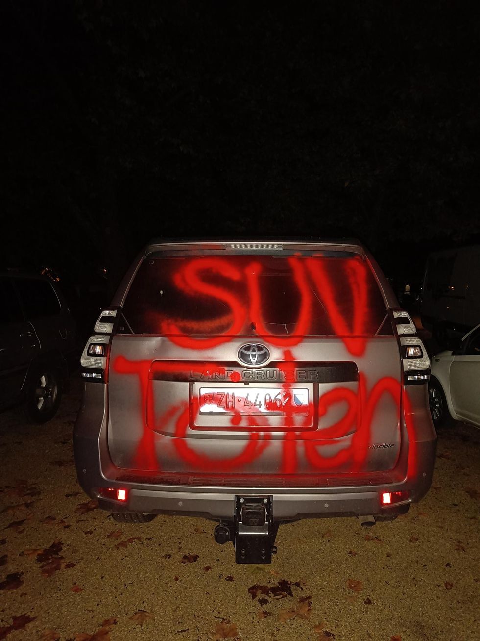 An SUV with 'SUVs kill' spray-painted on the boot of the vehicle