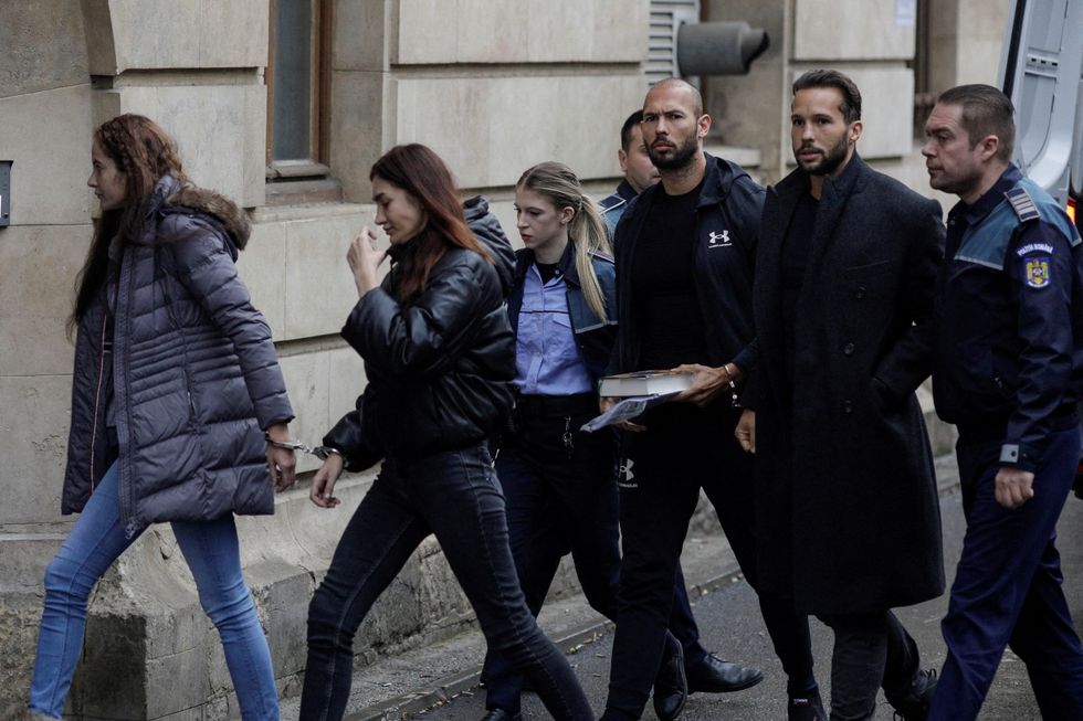 Andrew Tate and his brother Tristan are escorted by police officers outside the headquarters of the Bucharest Court of Appeal, in Bucharest, Romania, January 10, 2023. Inquam Photos/Octav Ganea via REUTERS ATTENTION EDITORS - THIS IMAGE WAS PROVIDED BY A THIRD PARTY. ROMANIA OUT. NO COMMERCIAL OR EDITORIAL SALES IN ROMANIA     TPX IMAGES OF THE DAY
