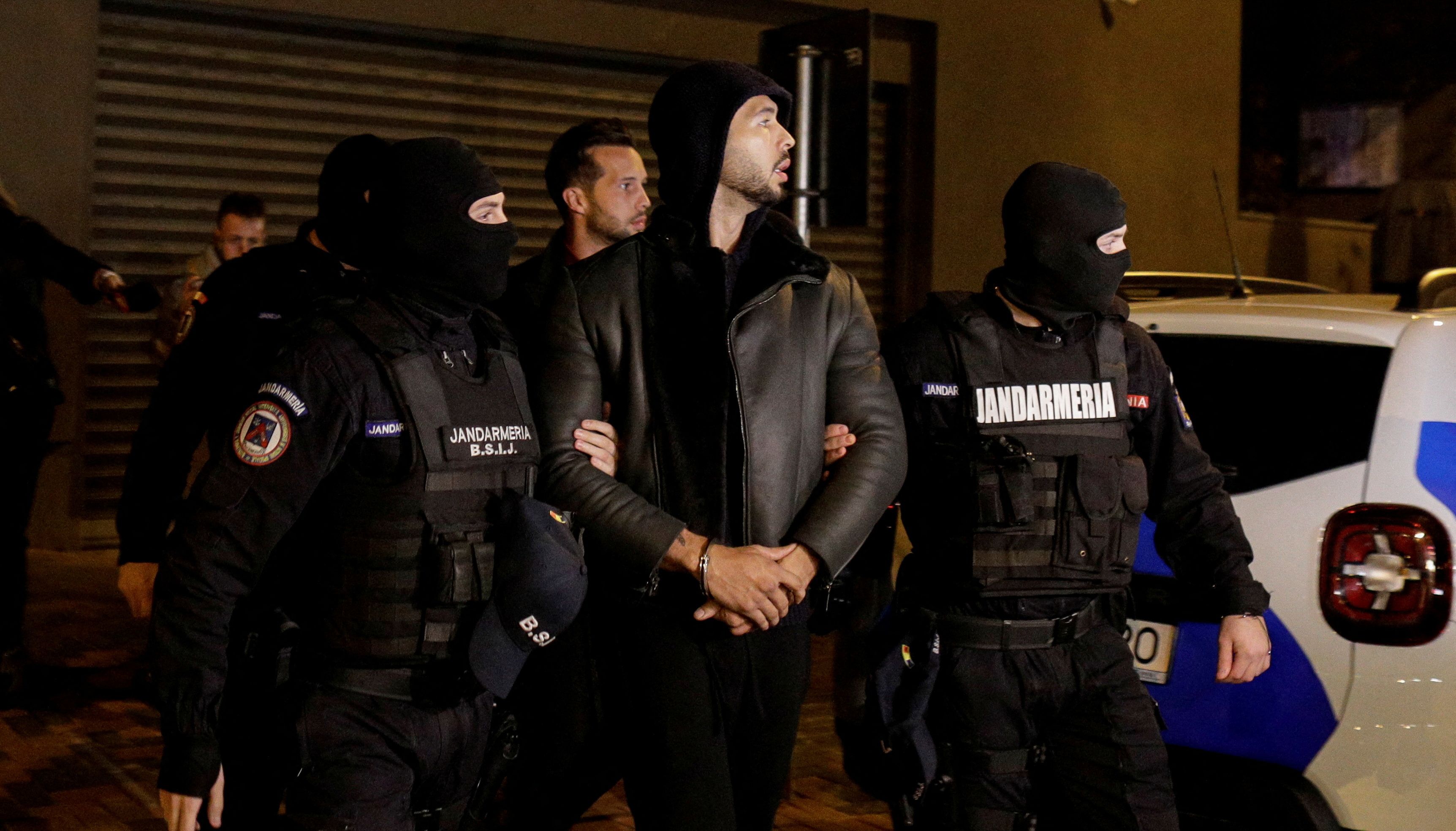 Andrew Tate and Tristan Tate are escorted by police officers.