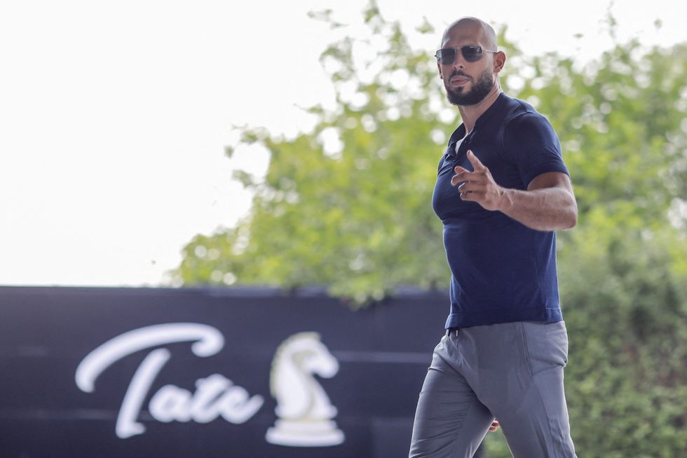 Andrew Tate gestures towards the media before delivering a press statement outside his house in Voluntari, Ilfov, Romania