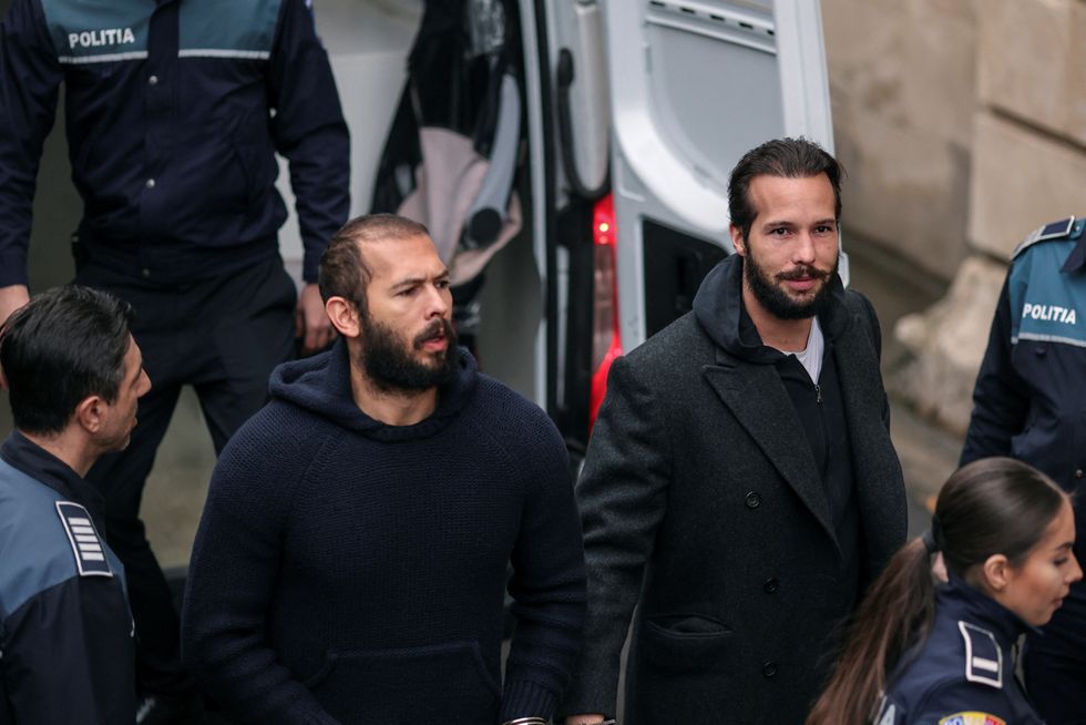 Andrew Tate talks to media representatives while being loaded inside a van outside the headquarters of the Bucharest Court of Appeal,