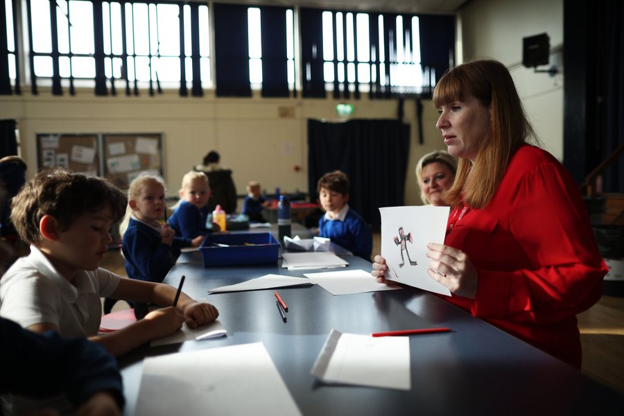 Angela Rayner holds up a drawing of what looks like a monster to some school children