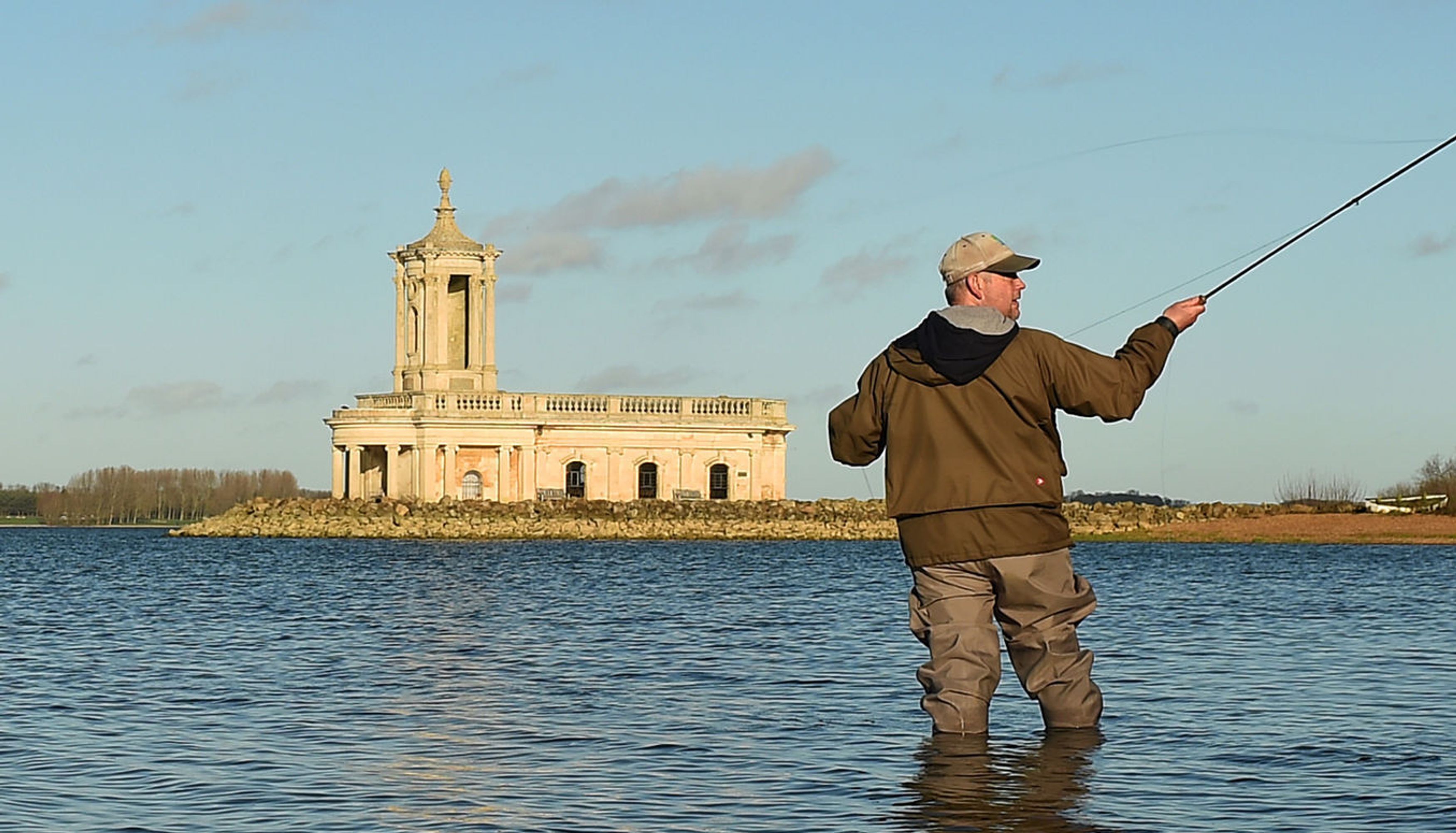 Angler Ade Naylor fishing in front of Normanton Church at Rutland Water reservoir in Rutland.