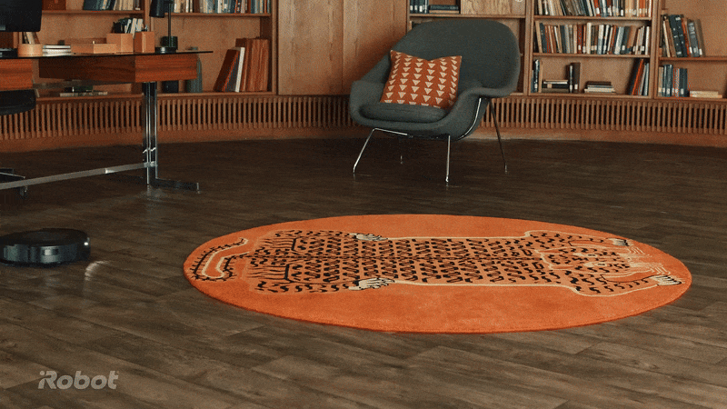 animated gif showing the irobot roomba vacuum cleaner cleaning a floor and then lifting itself into a carpet