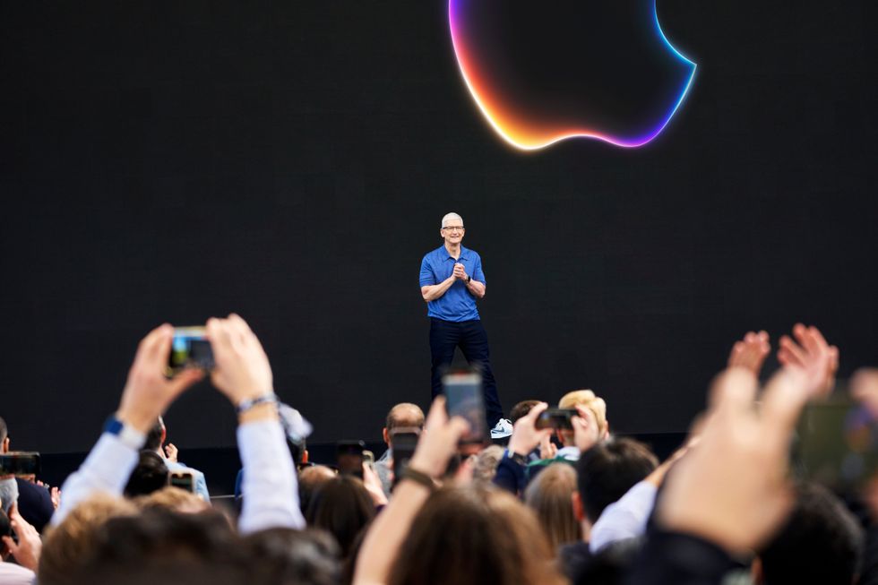 apple ceo tim cook on stage with an apple logo in the background during wwdc keynote