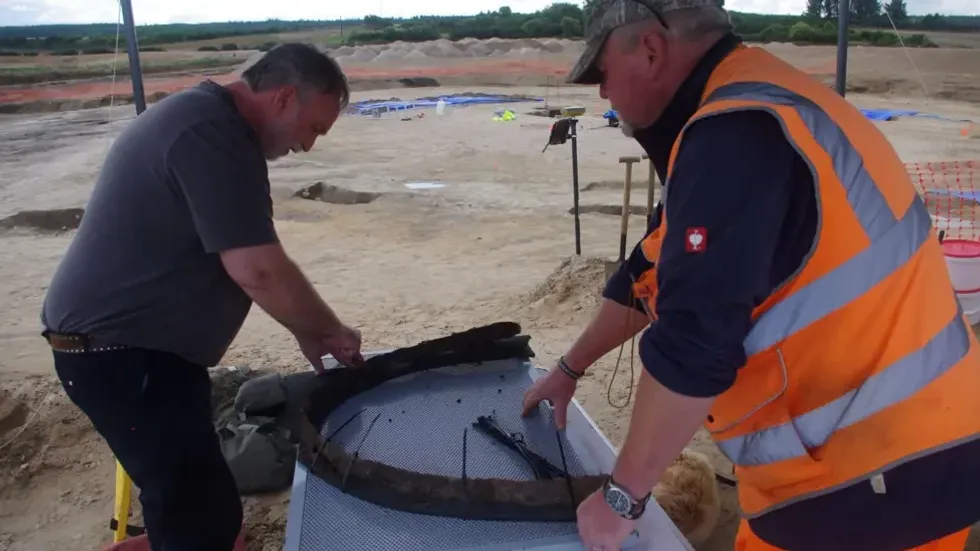 Archaeologists pore over a prehistoric chariot wheel at the site