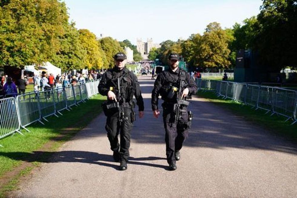 Armed police officers on patrol near to a police screening area on the Long Walk in Windsor for members of the public to queue in a one-way system to access Windsor Castle where they can pay their respects following the death of Queen Elizabeth II. Picture date: Sunday September 18, 2022.