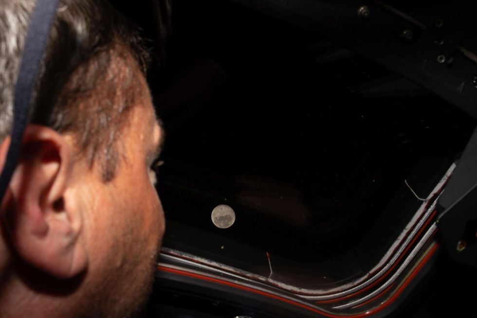 Artemis II commander Reid Wiseman looks out one of the Orion spacecraft's main cabin windows at the Moon