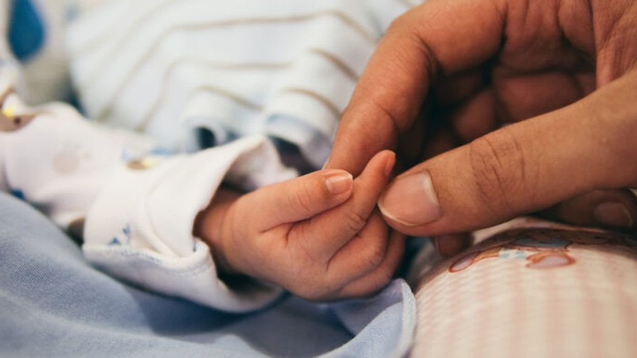 Baby holding hands with their parent in hospital (stock footage)