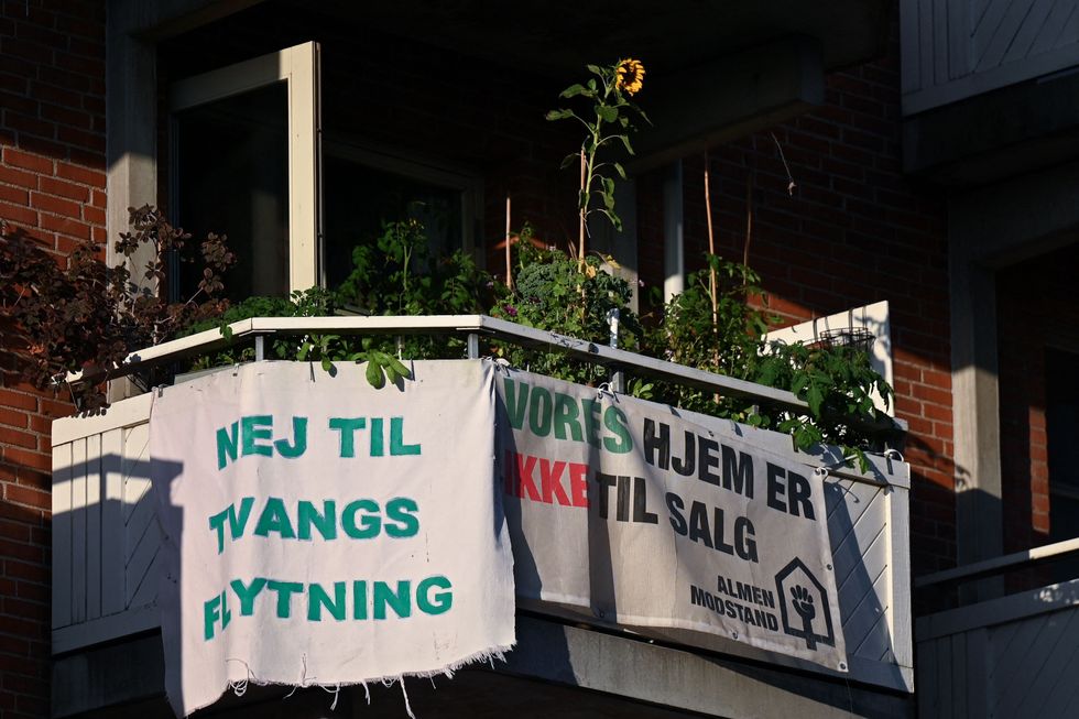 Banners with texts reading 'No to forced relocation' and 'Our homes are not for sale' are seen hanging out on a balcony of a residential building at Mjolnerparken housing estate in Copenhagen