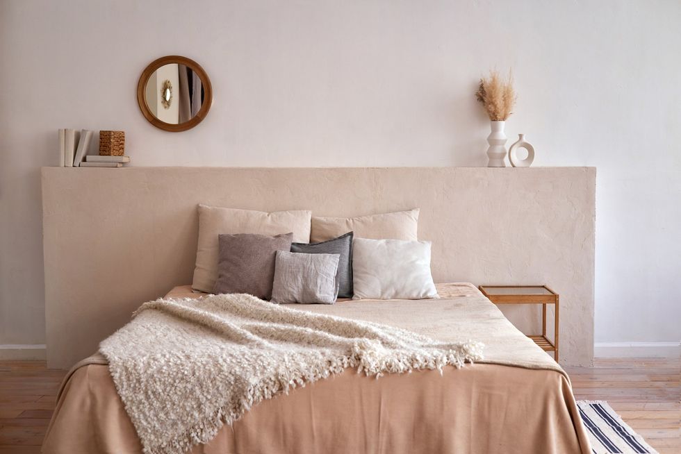 Bed covered in pillows and cushions, neutra colour scheme
