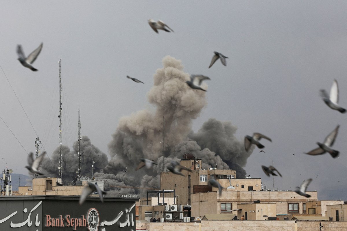 Birds fly as smoke rises following an explosion, after Israel and the U.S. launched strikes on Iran,